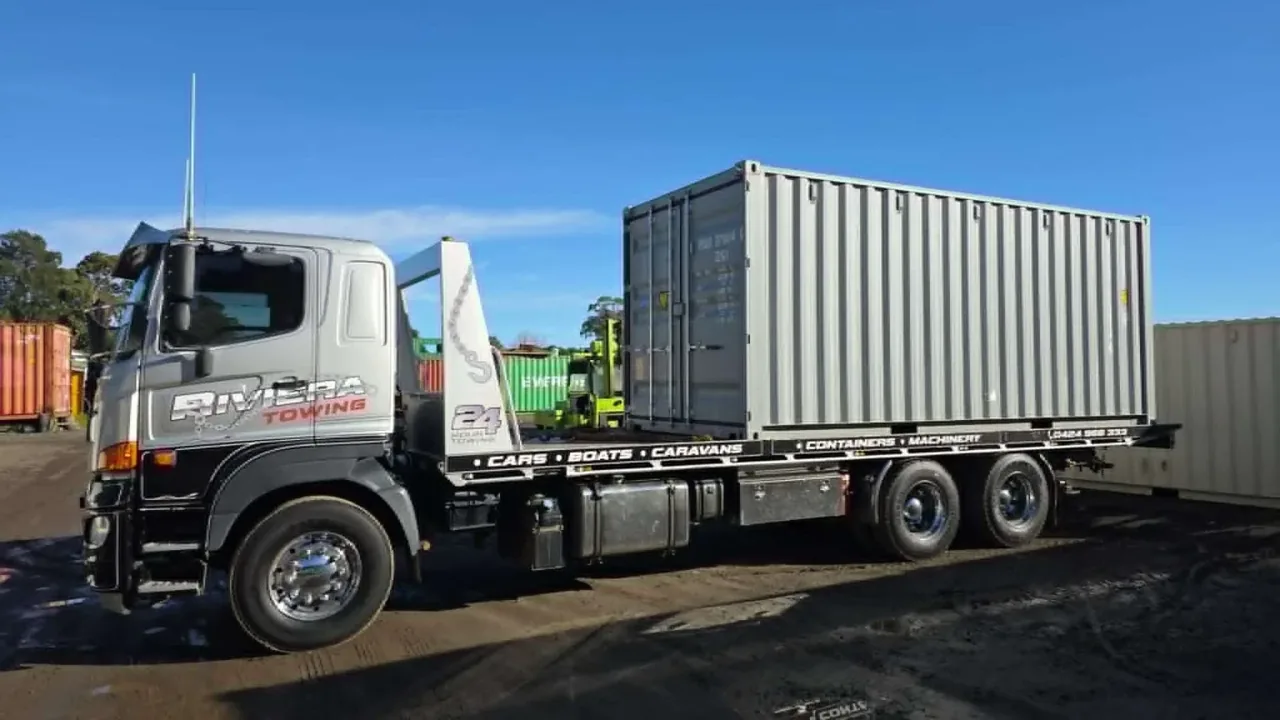 Riviera Towing tilt tray delivering a prime mover and shipping container to a depot